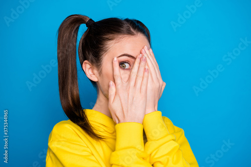Closeup photo of pretty lady two tails arms hiding eyes look fear watch cinema scary movie film wear yellow sweatshirt pullover isolated bright blue color background