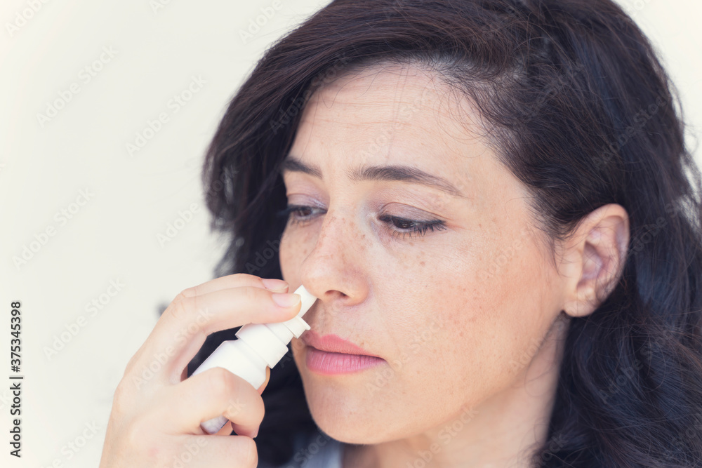 Female doing nasal irrigation by using normal saline solutiona spray isolated with copy space to add text Female doing nasal irrigation by using normal saline solutiona spray isolated with copy space to add text