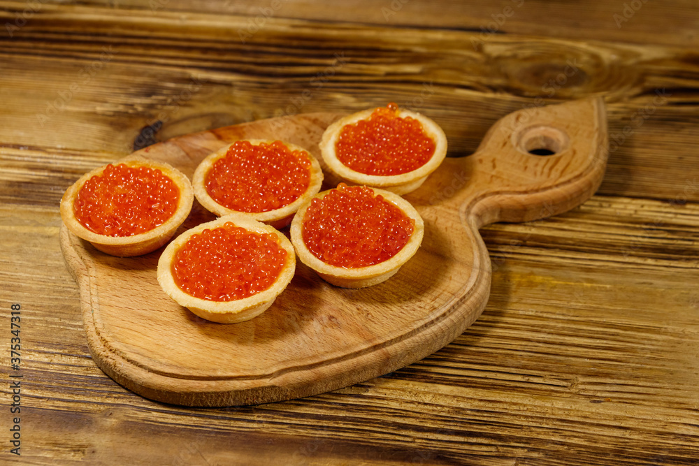 Tartlets with red caviar on a wooden table Tartlets with red caviar on a wooden table
