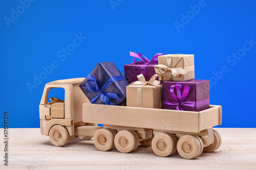 Wooden toy car with gifts. Boxes in festive packaging.