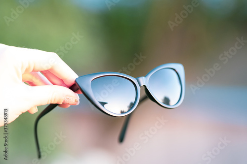 Cat eye sunglasses model hold by hand shoot in a summer day closeup. Selective focus