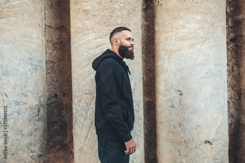 City portrait of handsome hipster guy with beard wearing black blank hoodie or sweatshirt with space for your logo or design. Mockup for print City portrait of handsome hipster guy with beard wearing black blank hoodie or sweatshirt with space for your logo or design. Mockup for print