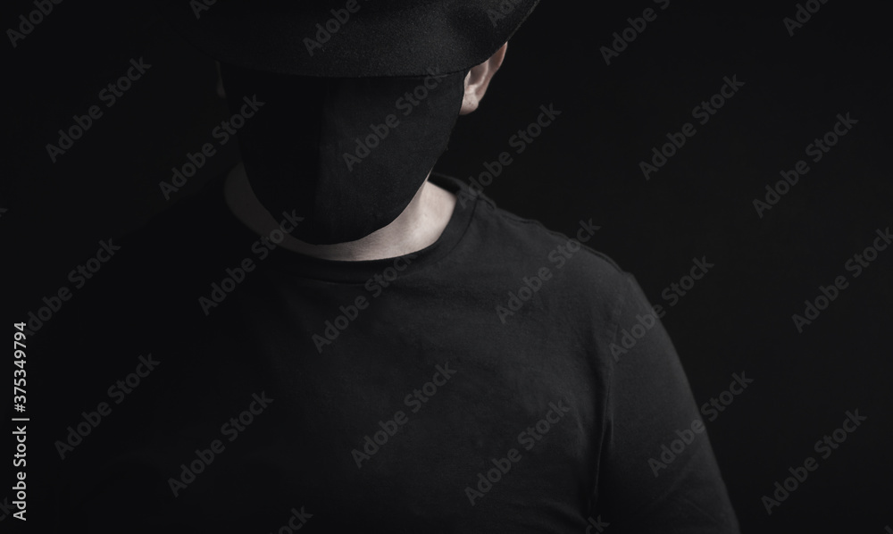 portrait of man with hat and black face mask looking down