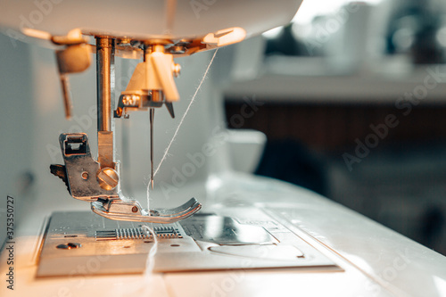 Mechanism of a sewing machine close up. White sewing machine needle with thread with copy space for text. The concept of the garment industry, technology. Photo for garment production.