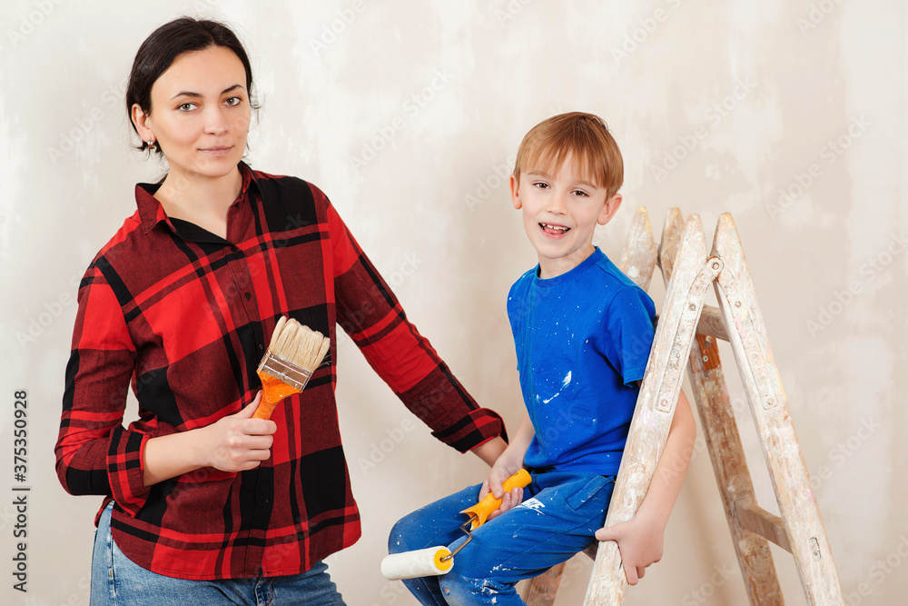 Repair in the apartment. Young family renovating their home together. Mother and kid paint a wall with a paint roller. Repair in the apartment. Young family renovating their home together. Mother and kid paint a wall with a paint roller.