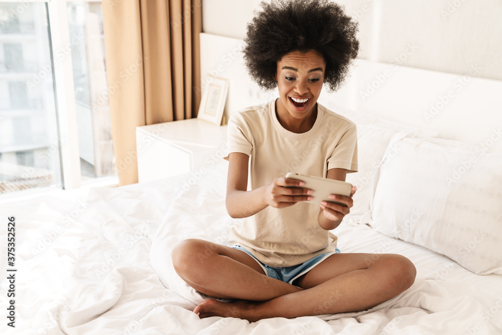 Happy young african woman playing games on mobile phone Happy young african woman playing games on mobile phone