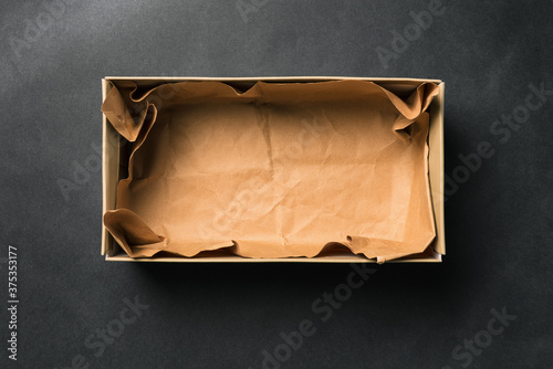 Open empty Shoe box, isolated on a black background. Crumpled brown paper. Packaging for men's and women's shoes or delivery of goods from the store. A top view of a flat layout photo
