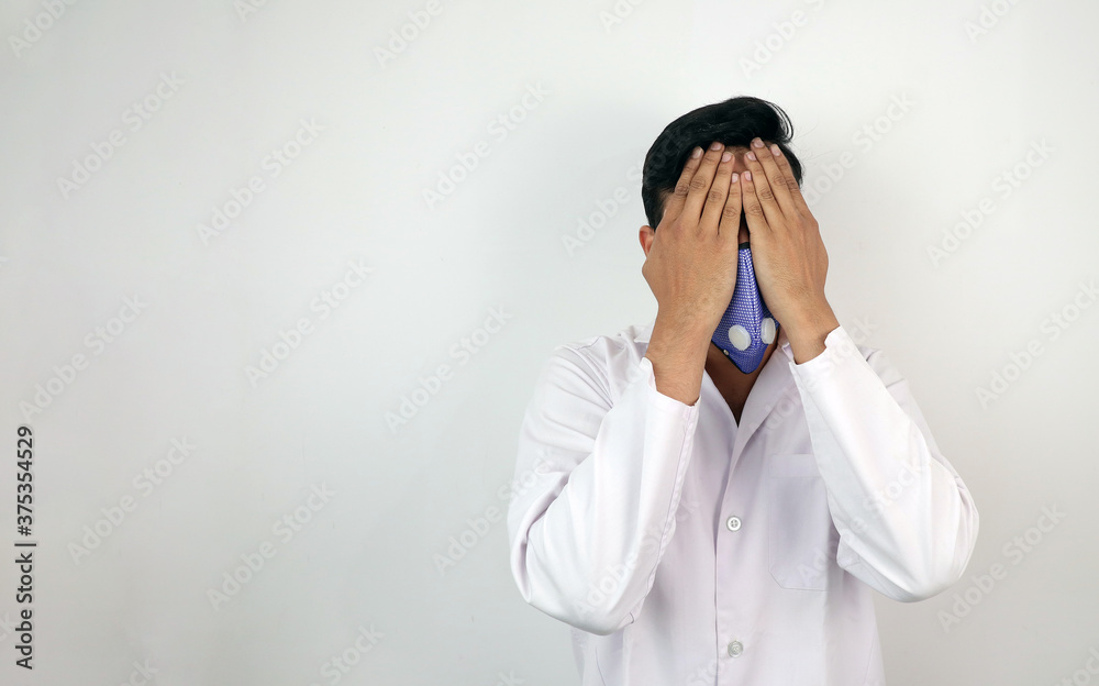a male medical professional in white coat and mask in white background. stressed out doctor hiding identity. concept image for viral infection a male medical professional in white coat and mask in white background. stressed out doctor hiding identity. concept image for viral infection