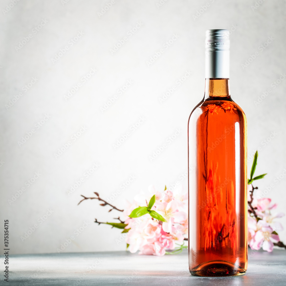 Rose wine bottle on the gray table and spring pink flowers. Rosado, rosato or blush wine tasting in wineshop, bar concept. Copy Space