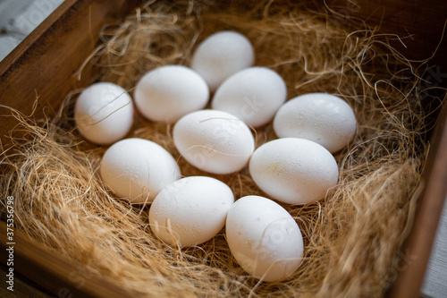 Eco-product. A wooden box of hay containing a ten white eggs. View from the top. Concept of natural and farm food
