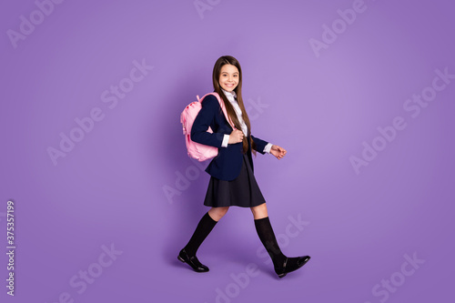 Full length body size profile side view of her she attractive cheerful small little schoolchild going back to school new season semester isolated violet lilac purple pastel color background