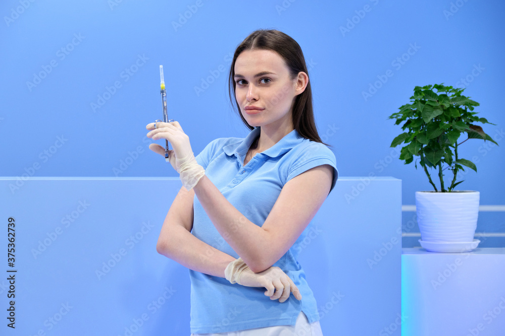 Beautiful young woman doctor with syringe in her hand, female nurse looks in camera Beautiful young woman doctor with syringe in her hand, female nurse looks in camera
