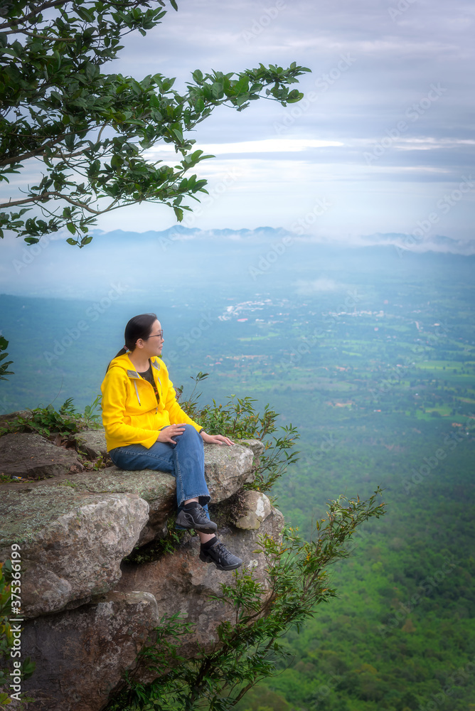 Fototapeta premium Asian woman tourist is sitting to see natural view with relax at cliff mountain at Sai Thong National Park at Chaiyaphum in Thailand.
