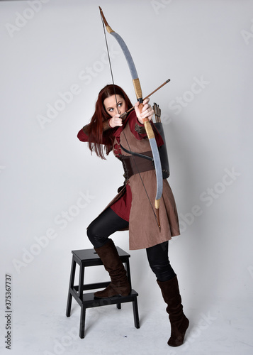 Tablou canvas Full length portrait of girl with red hair wearing  brown medieval archer costume