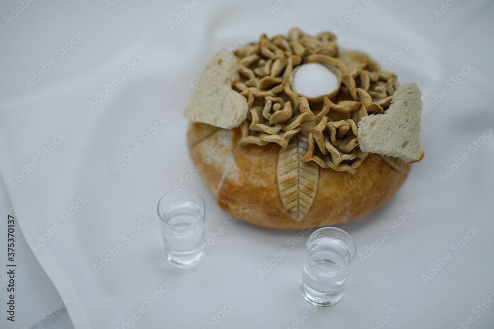 Traditional polish greeting the bride and groom by the parents with bread and salt. Vodka also in glasses Traditional polish greeting the bride and groom by the parents with bread and salt. Vodka also in glasses