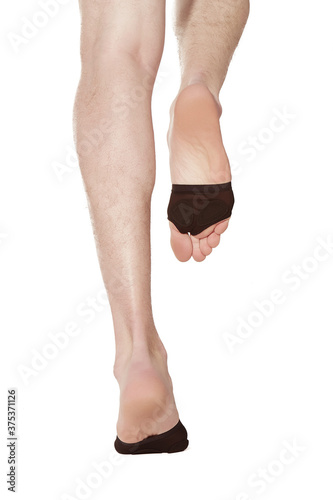 Detailed shot of male legs with cushion pads on forefeet for relief from metatarsals and foot pain, for running and walking. Feet in black protectors are walking on the yellow backdrop. 