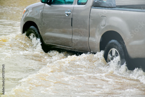 The pickup truck is passing the urban road which fulled of floodwater in the heavy raining day.
