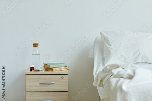 Horizontal no people shot of modern hospital ward interior with white walls, bed and night table, copy space photo