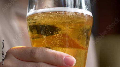 Beautiful attractive lovely girl with an unusual hairstyle in a cafe drinks beer from a glass. Close-up.