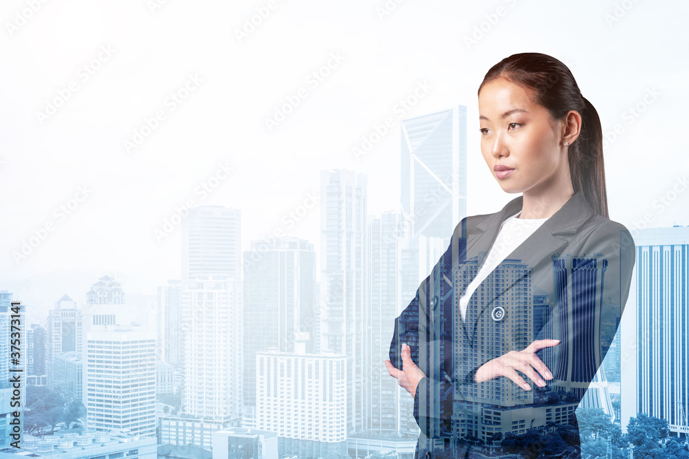 Prosperous Asian businesswoman in suit in crossed arms pose. Kuala Lumpur cityscape. The concept of woman in business. KL skyscrapers. Double exposure. Prosperous Asian businesswoman in suit in crossed arms pose. Kuala Lumpur cityscape. The concept of woman in business. KL skyscrapers. Double exposure.