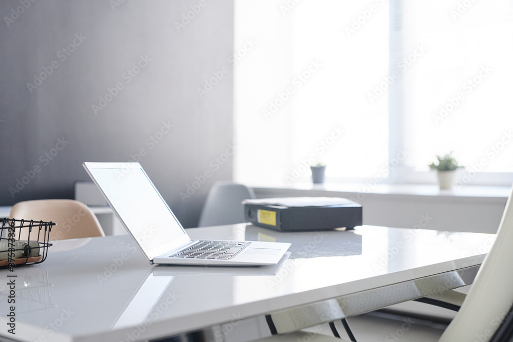 Minimalistic workplace interior in modern office room with laptop on desk, no people shot Minimalistic workplace interior in modern office room with laptop on desk, no people shot