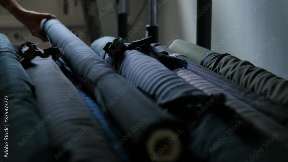 hand pulling fabric roll out of storage, moody lighting