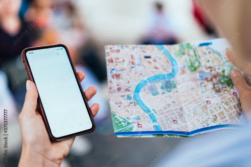 Tourist with smartphone and city map checking direction Tourist with smartphone and city map checking direction