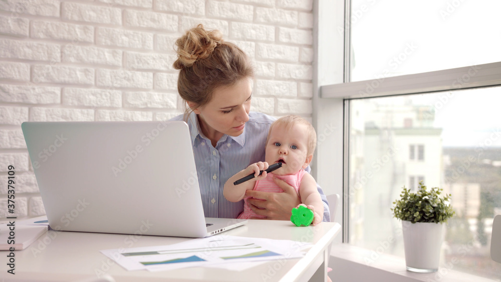 Working mom with child on table. Businesswoman holding toddler girl on hand Working mom with child on table. Businesswoman holding toddler girl on hand