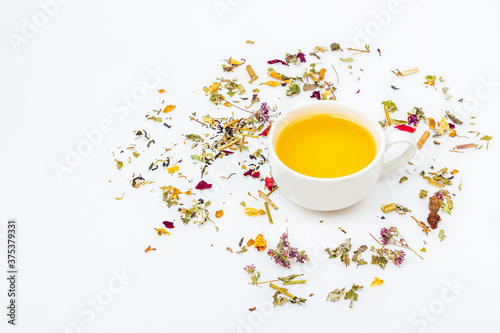 Flat lay layout of cup of green tea with assortment of different dry tea leaf and ginger on white background, copy space for text. Organic herbal, green asian tea for the tea ceremony.