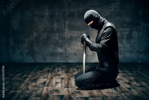 Fotografie Warrior man sitting on floor posing with a sword