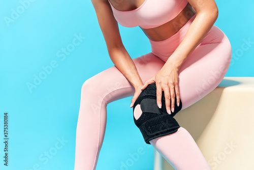 Woman suffering from knee pain on blue background
