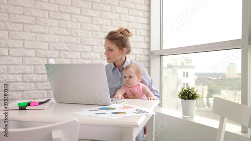 Businesswoman with kid working with documents. Freelancer at maternity leave