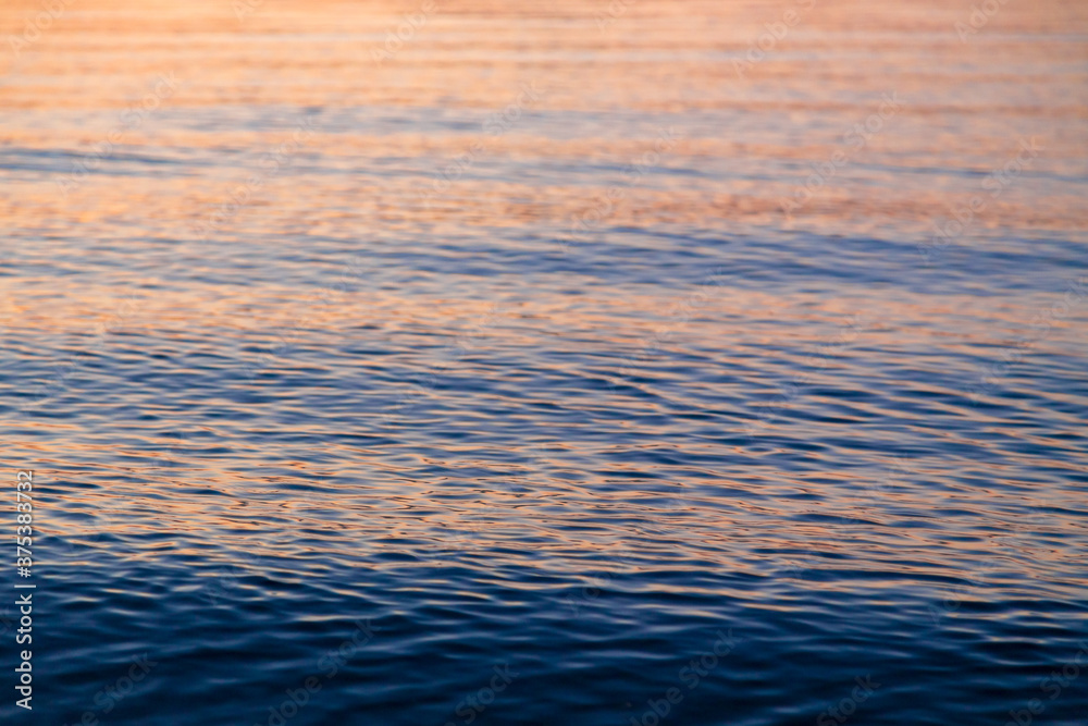 Clear water texture in blue and orange. Background of the ocean and the sea backlit by the sun. Natural water