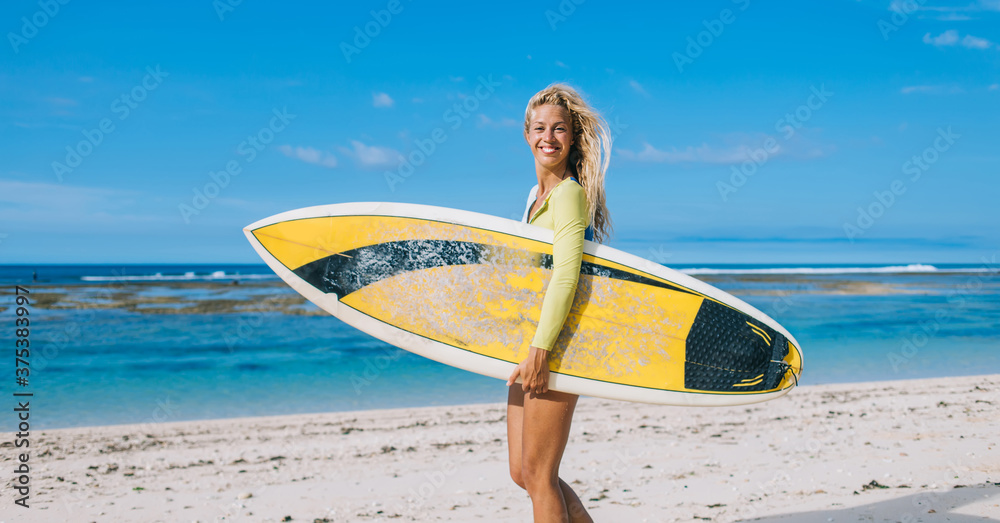 Joyful young athletic woman with surf board having fun on seaside