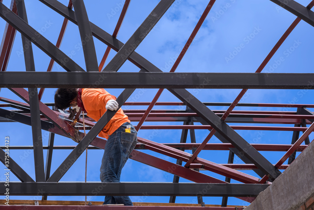 Asian construction worker without welding mask is welding metal on roof structure against blue sky background, unsafe working concept