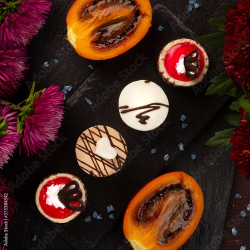 Round cakes on a stone tray with flowers and tamarillo