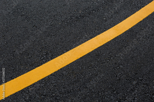 Yellow line on asphalt road texture background © PARINYA