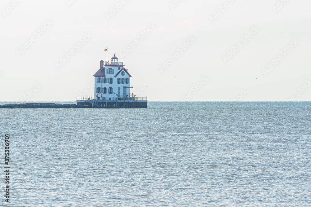 Lighthouse in calm water of bay in ocean or lake