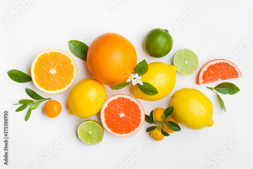 Obraz na plátně Citrus fruits and green leaves on white table top view