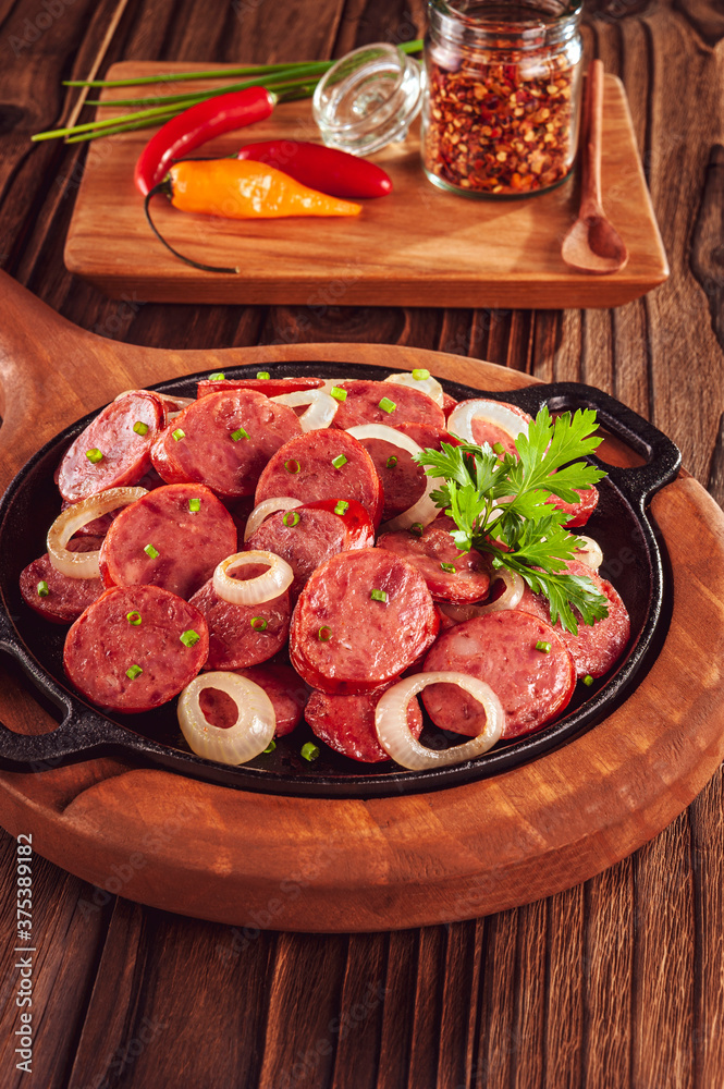 Sliced smoked calabrese sausage with onion and calabrese pepper in a wooden background - Brazilian appetizer Sliced smoked calabrese sausage with onion and calabrese pepper in a wooden background - Brazilian appetizer