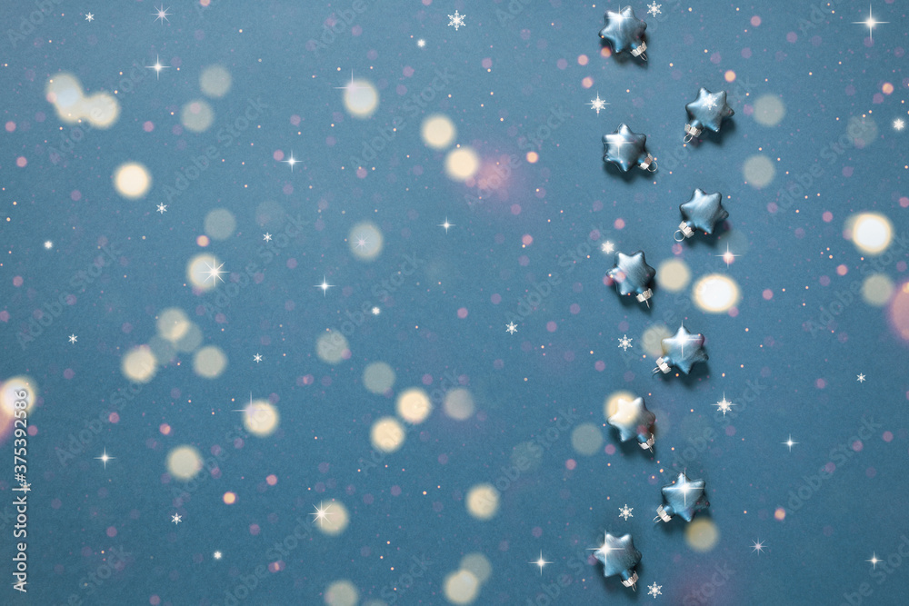 Christmas decorative stars on a blue background with bokeh lights. Holiday greeting card.