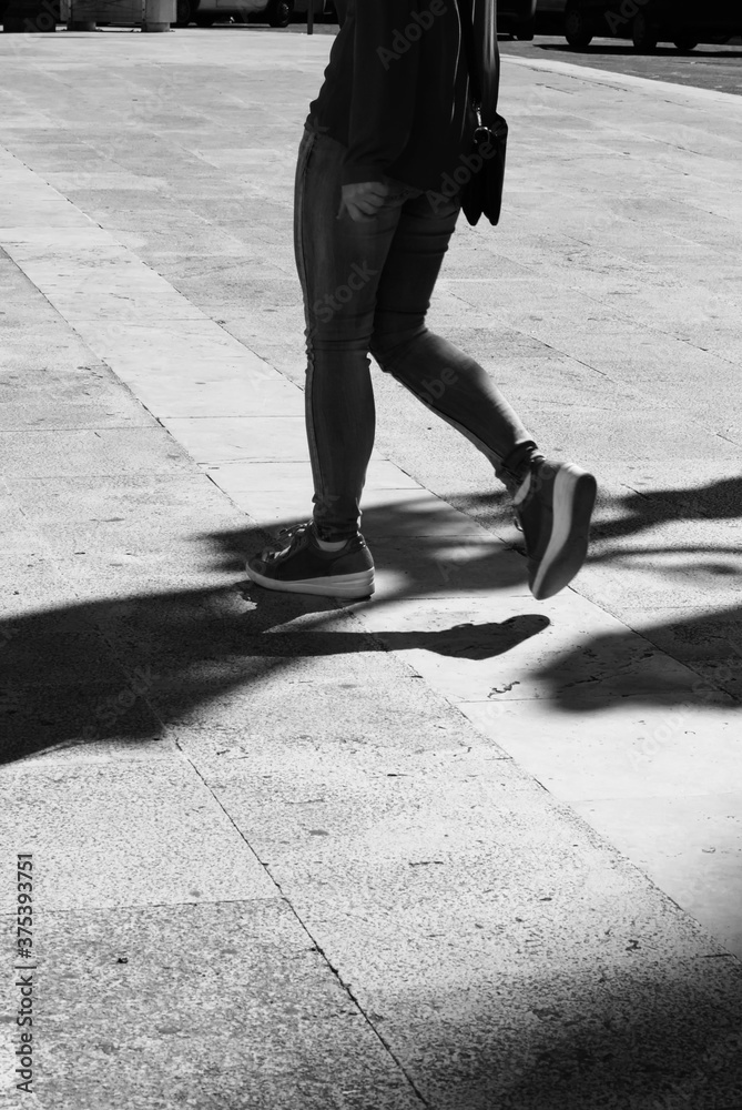 Girl walking with elongated shadow in black and white.Black and white. Shadow and light, girl silhouette Girl walking with elongated shadow in black and white.Black and white. Shadow and light, girl silhouette