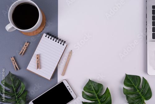 Office desk with coffee laptop and phone on white grey background with copy space. Technology and business on workspace with green leaves. Flat lay and top view.