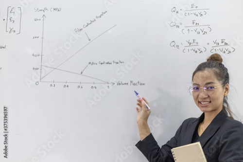 Asian teacher is teaching and writing on a whiteboard.
