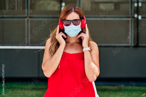 Young woman with a mask listening to music. Concept of new normality and fight against the virus.