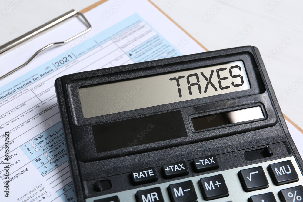 Calculator with word Taxes and document on table, closeup Calculator with word Taxes and document on table, closeup