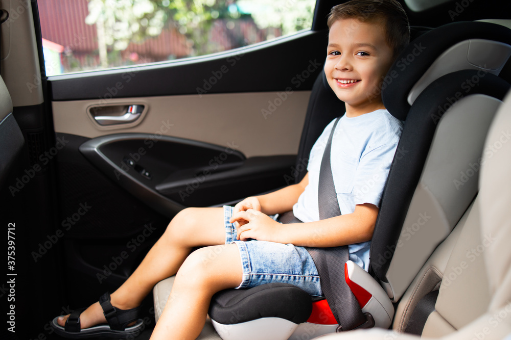 A boy sitting in car seat locked with safety belts