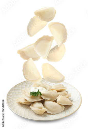 Many tasty dumplings falling on white background