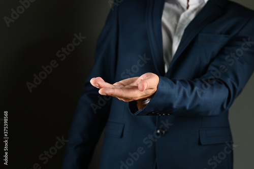 The man in the suit holds out his palm.