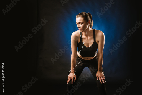 Slim sport woman doing exercises on the black studio background